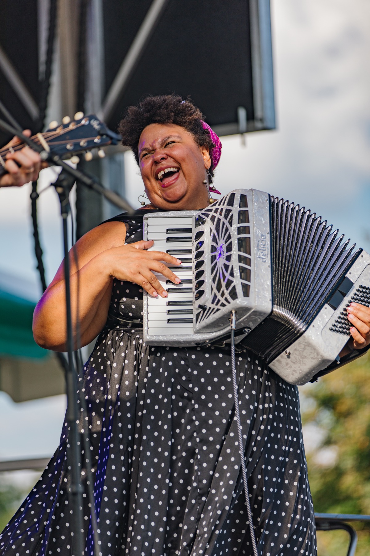 A musician singing and playing accordion on an outdoor stage